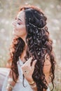 Beautiful young woman with long curly hair dressed in boho style dress posing in a field with dandelions Royalty Free Stock Photo