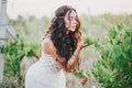 Beautiful young woman with long curly hair dressed in boho style dress posing in a field with dandelions Royalty Free Stock Photo