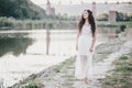 Beautiful young woman with long curly hair dressed in boho style dress posing near lake Royalty Free Stock Photo