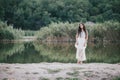 Beautiful young woman with long curly hair dressed in boho style dress posing near lake Royalty Free Stock Photo