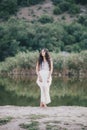 Beautiful young woman with long curly hair dressed in boho style dress posing near lake Royalty Free Stock Photo