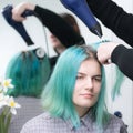 Beautiful young woman with long green hair while drying and styling hair in beauty salon
