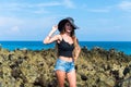 Beautiful young woman with long hair and hat stands on the background of big wave splashes during high tide in the Royalty Free Stock Photo