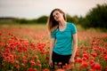 Beautiful young woman with long hair standing on field with red poppies. Royalty Free Stock Photo