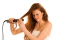 Beautiful young woman with long hair using hair straighteners is Royalty Free Stock Photo