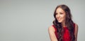 Beautiful young woman with long healthy curly hair and bright make up wearing red dress  on grey studio Royalty Free Stock Photo