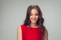 Beautiful young woman with long healthy curly hair and bright make up wearing red dress isolated on grey studio Royalty Free Stock Photo