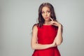 Beautiful young woman with long healthy curly hair and bright make up wearing red dress isolated on grey studio Royalty Free Stock Photo