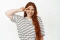 Beautiful young woman with long red hair, ginger girl showing peace v-sign near face skin with freckles, smiling happy Royalty Free Stock Photo