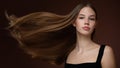Beautiful young woman with long straight hair and makeup. Brown background