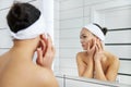 Beautiful young woman look in mirror massaging face Royalty Free Stock Photo