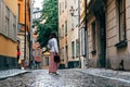 Beautiful young woman is looking back in a picturesque and narrow cobblestoned street