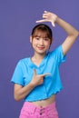 Beautiful young woman looking at camera and gesturing finger frame while standing against purple background Royalty Free Stock Photo