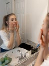 Beautiful Young Woman Looking and Examining Her Face and Makeup in Her Home Bathroom Mirror in the Morning Getting Ready for a Goo Royalty Free Stock Photo