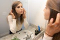 Beautiful Young Woman Looking and Examining Her Face and Makeup in Her Home Bathroom Mirror in the Morning Getting Ready for a Goo Royalty Free Stock Photo