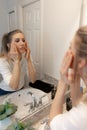 Beautiful Young Woman Looking and Examining Her Face and Makeup in Her Home Bathroom Mirror in the Morning Getting Ready for a Goo Royalty Free Stock Photo