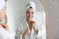 Beautiful young woman looking at herself in bathroom mirror Royalty Free Stock Photo