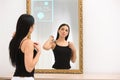 Beautiful woman looking at herself in smart mirror indoors