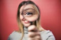 Beautiful young woman looking through magnifying glass at the camera over pink background Royalty Free Stock Photo