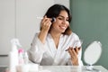 Beautiful young woman looking at mirror, applying blush Royalty Free Stock Photo