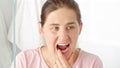 Beautiful young woman looking in the mirror and checking her teeth with finger. Concept of teeth health, self checking mouth and Royalty Free Stock Photo