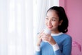 Beautiful young woman is looking out the window and holding a cup of coffee. Royalty Free Stock Photo