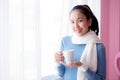 Beautiful young woman is looking out the window and holding a cup of coffee. Royalty Free Stock Photo