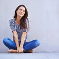 Life is just grand. A beautiful young woman looking thoughtful while sitting cross-legged on the floor. Royalty Free Stock Photo