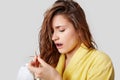 Beautiful young woman looks with dissatisfaction at her wet damaged hair, wears yellow bathrobe, needs to change shampoo, isolated Royalty Free Stock Photo