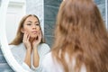 Beautiful young woman looks at her face in the mirror Royalty Free Stock Photo