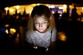 Beautiful young woman looks into the phone. her face is lit by the light from the phone. the portrait was made at night. Royalty Free Stock Photo