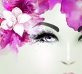 Beautiful young woman looks straight. Light blooming orchid decorated abstract hair. Royalty Free Stock Photo