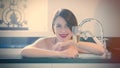 Beautiful young woman lying in the bath and holding a glass of c Royalty Free Stock Photo