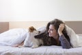 beautiful young woman lying on bed under the white cover with her cute small dog. Home, indoors and lifestyle Royalty Free Stock Photo