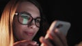 Beautiful young Woman Lying in Bed, Using Smart Phone and Smiling before Sleep. Woman using Cellphone on bed at Night Royalty Free Stock Photo