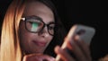 Beautiful young Woman Lying in Bed, Using Smart Phone and Smiling before Sleep. Woman using Cellphone on bed at Night Royalty Free Stock Photo