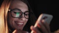 Beautiful young Woman Lying in Bed, Using Smart Phone and Smiling before Sleep. Woman using Cellphone on bed at Night Royalty Free Stock Photo