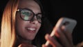 Beautiful young Woman Lying in Bed, Using Smart Phone and Smiling before Sleep. Woman using Cellphone on bed at Night Royalty Free Stock Photo