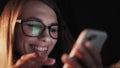 Beautiful young Woman Lying in Bed, Using Smart Phone and Smiling before Sleep. Woman using Cellphone on bed at Night Royalty Free Stock Photo