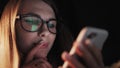 Beautiful young Woman Lying in Bed, Using Smart Phone and Smiling before Sleep. Woman using Cellphone on bed at Night Royalty Free Stock Photo