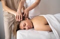 Beautiful young woman lying with closed eyes and having head massage at spa in four hands. masseur student massage Royalty Free Stock Photo