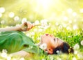 Beautiful young woman lying on the field in green grass and blowing dandelion flowers Royalty Free Stock Photo