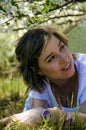 Beautiful Young Woman lying on a field, green grass and dandelion flowers. Outdoors Enjoy Nature. Healthy Smiling Girl lying in Royalty Free Stock Photo