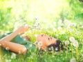 Beautiful young woman lying on green grass and blowing dandelions Royalty Free Stock Photo