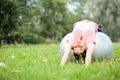Beautiful young woman lying on her back on a fitness ball and stretching in a park Royalty Free Stock Photo