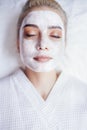 Beautiful young woman lying with her eyes closed and white rejuvenating mask Royalty Free Stock Photo