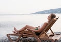 The beautiful young woman lying on the sun lounger listening to the music Royalty Free Stock Photo