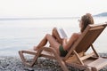 The beautiful young woman lying on the sun lounger reading a book Royalty Free Stock Photo