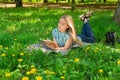 Beautiful young woman lying, thinking and writing in her diary on the grass with flowers. Front view. Royalty Free Stock Photo