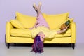 beautiful young woman lying upside down on yellow couch Royalty Free Stock Photo